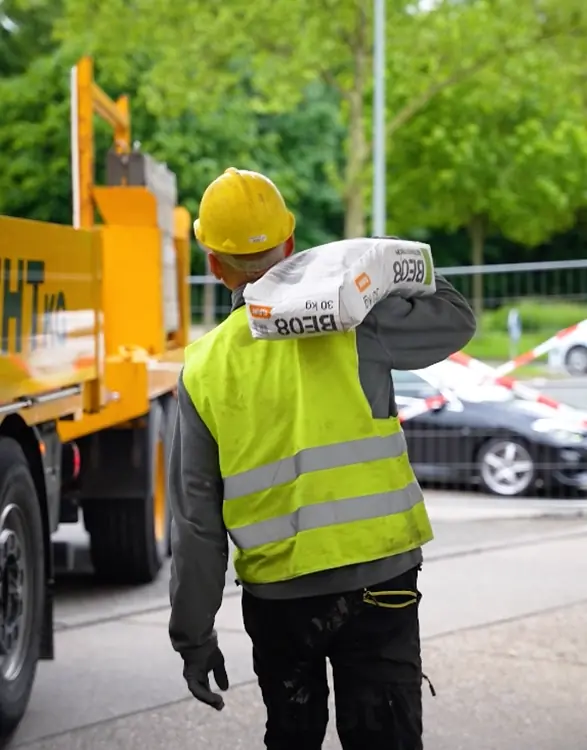 Monteur bringt Material vom Kranfahrzeug zur Baustelle