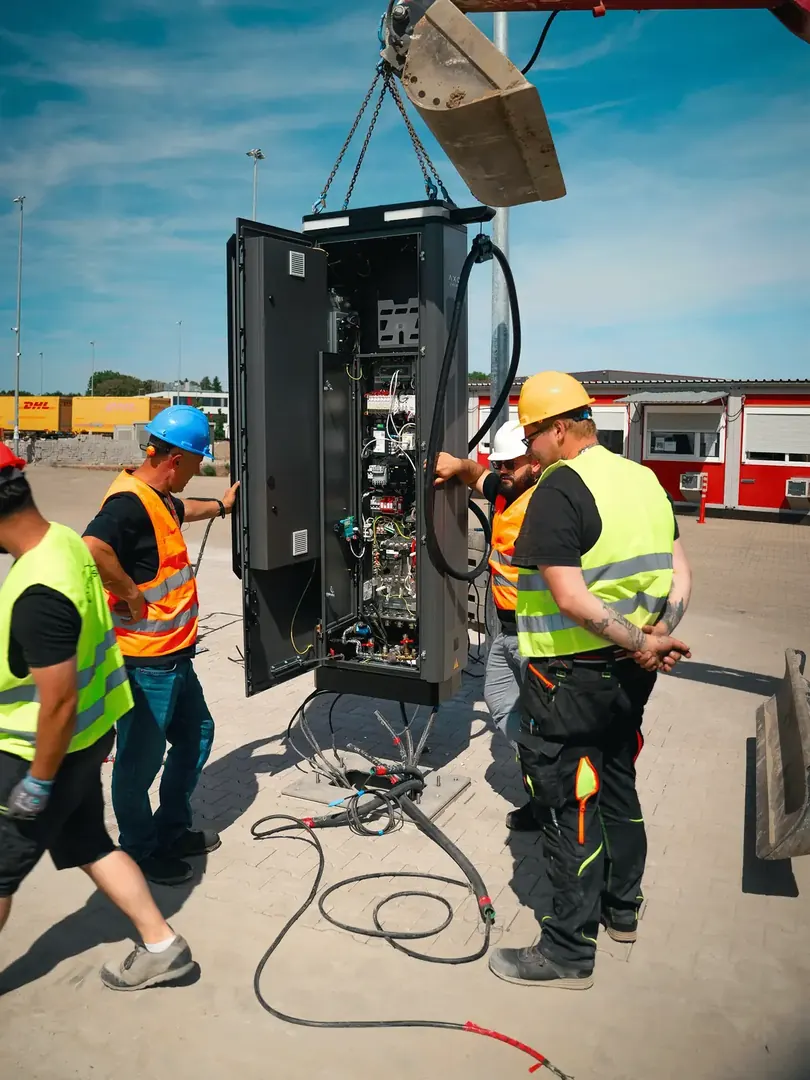 Montageteam setzt eine Ladestation auf einem Betriebshof